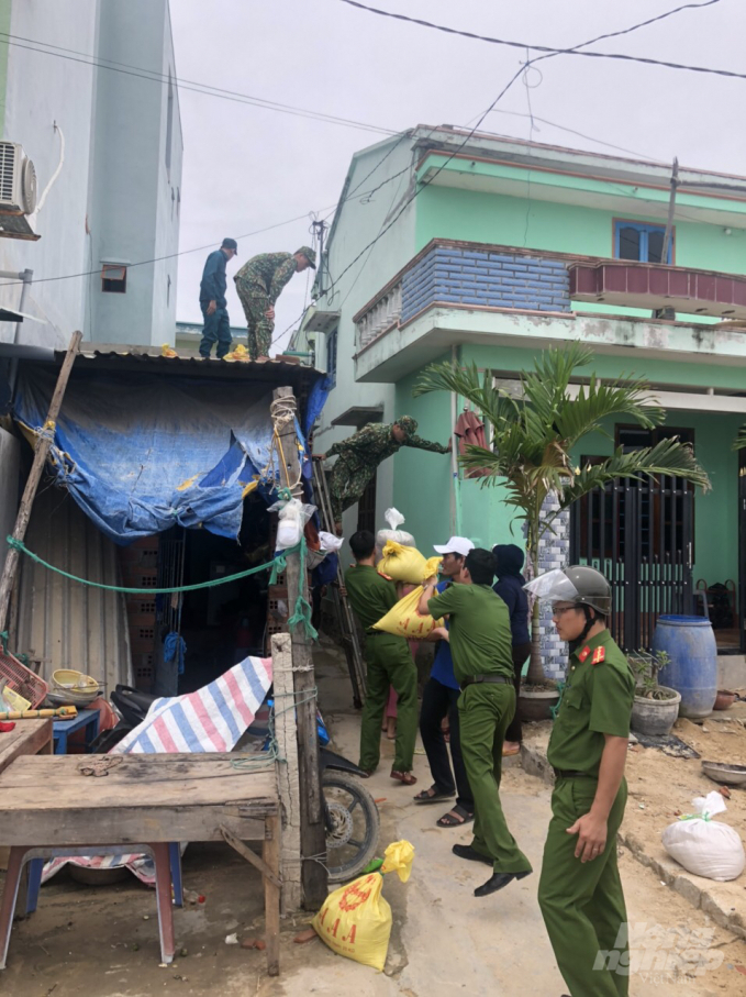 Bộ đội giúp người dân xã biển Nhơn Hải (TP Quy Nhơn, Bình Định) đưa những bao cát lên đè những mái tôn nhà đơn sơ. Ảnh: Vũ Đình Thung.