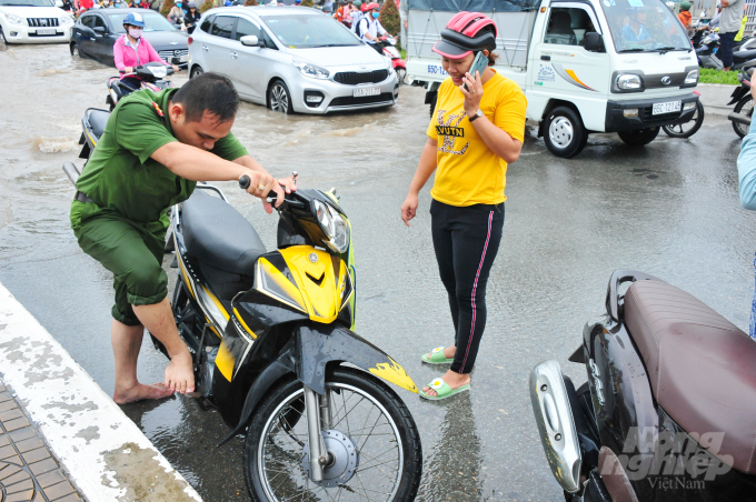 Tại các điểm ngập, có hàng chục công an, bảo vệ dân phố và thanh niên tình nguyện bì bõm đẩy xe giúp người dân qua đoạn ngập sâu, nước chảy xiết và giúp nổ máy xe.