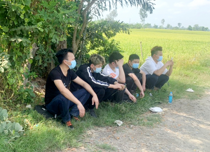 5 người Trung Quốc đang ngồi chờ người đưa đi xuất cảnh trái phép sang Campuchia ở một vườn cây ngoài đồng vắng, ở ấp Bình Thành, xã Bình Mỹ, huyện Châu Phú (An Giang) bị lực lượng chức năng phát hiện bắt giữ. Ảnh: Nghiêm Túc.