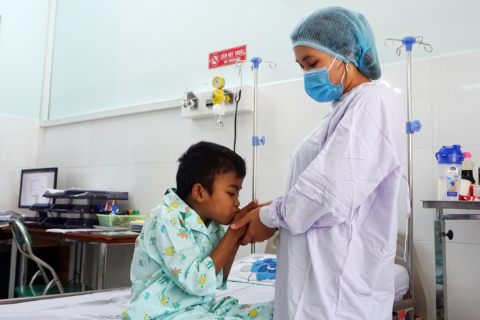 Nhìn thấy mẹ, cậu bé Thổ Văn Minh nắm chặt bàn tay mẹ. Ảnh: Nguyễn Thủy.