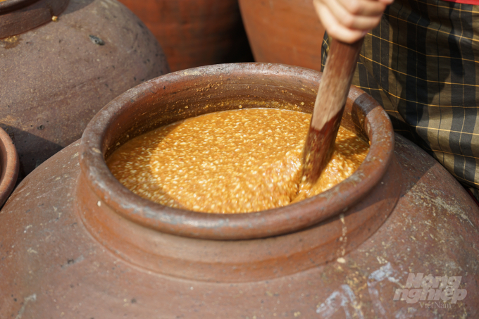 Trong thời gian ngâm ủ tương, hàng ngày người làm tương sẽ mở nắp chum, khuấy đều cho thêm nước. Trời nắng thì mở nắp phơi, trời mưa thì phủ kín miệng chum để tránh nước mưa. Ảnh: Hoàng Dân.