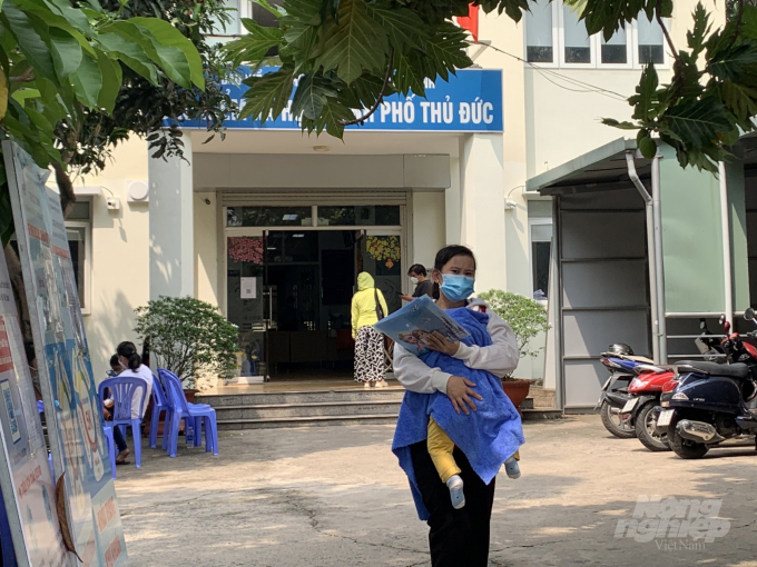 Vì không có người trông con nên chị Huỳnh Thị Kim Ng. phải bồng cả con đến BHXH Thành phố Thủ Đức để làm thủ tục. Ảnh: Nguyễn Thủy.