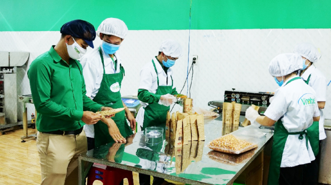 Anh Nguyễn Hoàng Đạt (bìa trái), Giám đốc Công ty TNHH Vinahe kiểm tra quy trình đóng gói sản phẩm hạt điều chế biến sâu tại dây chuyền sản xuất của Công ty. Ảnh: Kiểm Đông.