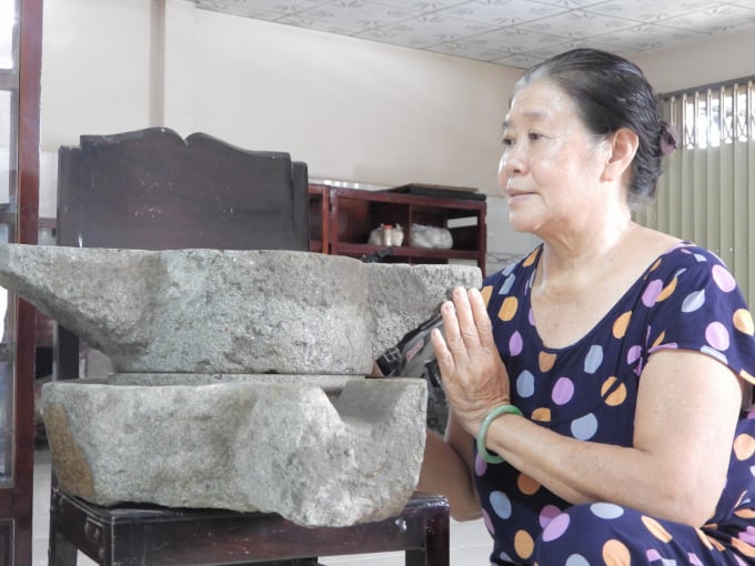 Bà Mỹ Vân bên kỷ vật cối xay muối đã giúp cơ sở phát triển như ngày hôm nay. Ảnh: Hồng Thủy