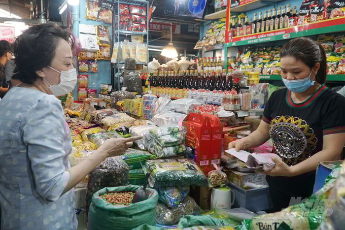 Bà Phạm Khánh Phong Lan, Trưởng ban Ban Quản lý An toàn thực phẩm TP.HCM kiểm tra hóa đơn chứng từ tại sạp kinh doanh chợ An Đông, quận 5. Ảnh: Nguyễn Thủy.