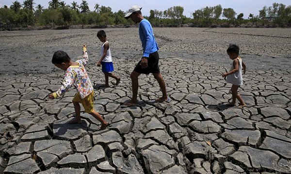 Người cha cùng đàn con đi qua một ngư trường khô cằn gần Manila. Ảnh: Romeo Ranoco / Reuters
