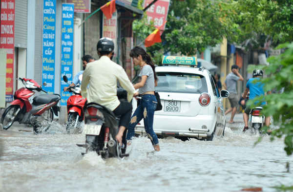 Mặc dù thời tiết lức gần trưa đã hửng nắng nhưng người dân vẫn bì bõm qua đoạn đường ngập nước