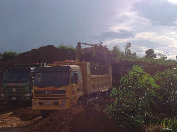 Máy múc đang múc đất lên xe để chở đi bán