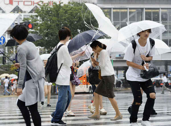 Nhiều người đi bộ trong điều kiện thời tiết gió mạnh do bão Mindulle tấn công Tokyo (Nhật Bản) vào ngày 22/8/2016. Cơn bão quét qua Tokyo và các khu vực xung quanh đã buộc hơn 400 chuyến bay nội địa phải hủy bỏ và làm gián đoạn dịch vụ xe lửa. Ảnh: Akiko Matsushita / Kyodo News qua AP