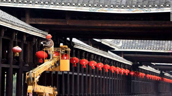 Một công nhân treo đèn lồng đỏ trên một cây cầu ở quận Sanjiang Dong, khu tự trị Choang Quảng Tây, Trung Quốc.