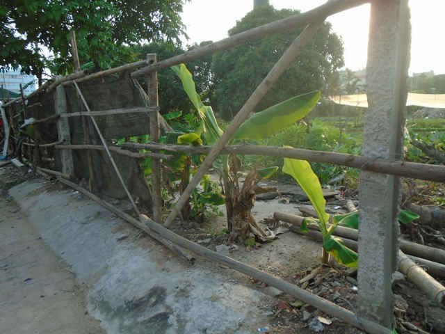hàng loạt các cột trụ bê tông kiên cố, xen kẽ với đó là các loại tre giáo, phong bạt vây kín ngăn cách giữa phần đất lưu không với vỉa hè đường gom chân cầu Thanh Trì.