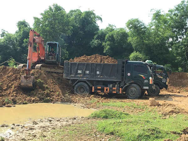 Máy xúc đang hoạt động hết công suất múc đất đổ lên xe