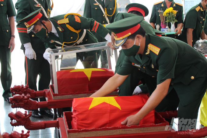 Lá Quốc kỳ phủ lên hài cốt từng liệt sĩ trước khi về với đất mẹ. Ảnh: QB.