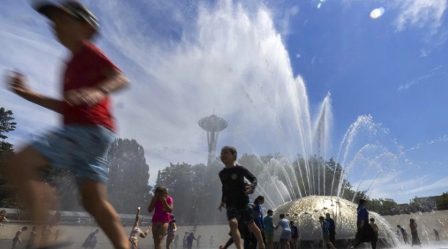 The International Fountain at Seattle Center is packed with children as they run from the water that is showering on them Wednesday, July 27, 2022 in Seattle. Photo: Ellen M. Banner/The Seattle Times via AP