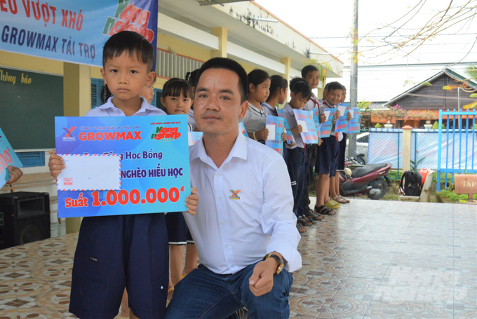 Đại diện Công ty TNHH Thức ăn Thủy sản GrowMax, ông Vũ Văn Toản trao học bổng cho học sinh có hoàn cảnh khó khăn Trường Tiểu học Vĩnh Bình Bắc 3. Ảnh: Trung Chánh.