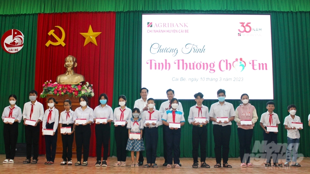 Lãnh đạo ngân hàng Agribank chi nhánh tỉnh Tiền Giang trao quà cho trẻ em mồ coi, hoàn cảnh đặc biệt khó khăn trên địa bàn huyện Cái Bè. Ảnh: Quốc Trí.