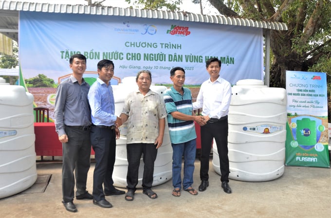 Đại diện Tập đoàn Tân Á Đại Thành trao bồn nước cho người dân.