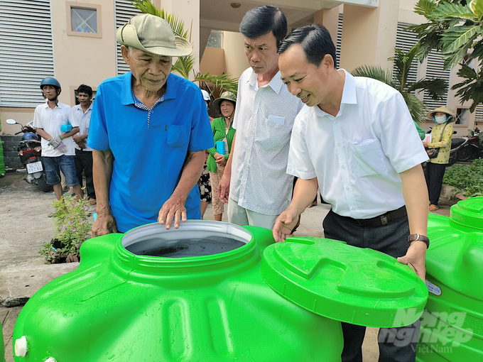 Ông Nguyễn Ngọc Thắng (bìa phải), Trưởng Văn phòng đại diện Báo Nông nghiệp Việt Nam khu vực ĐBSCL trao bồn nước cho bà con xã Tân Mỹ, huyện Trà Ôn, tỉnh Vĩnh Long sáng ngày 24/5/2023. Ảnh: Minh Đảm.