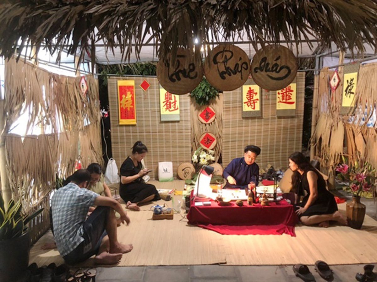 hai-phong-phuc-dung-cho-que-thoi-nha-mac-100549_982.jpg Một gian hàng tái hiện lại cảnh thầy đồ viết thư pháp bằng chữ Hán. Ảnh: Đinh Mười.