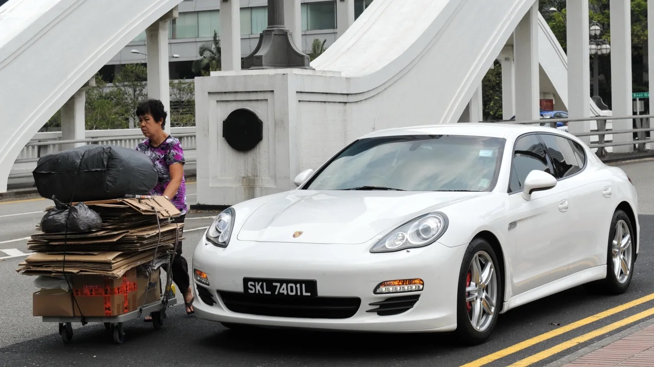 171030161732-singapore-cars-pricey-4-093735_624.jpg Một người phụ nữ đẩy xe chở rác tái chế qua một chiếc ô tô đắt tiền trên đường phố ở Singapore. Ảnh: AFP.