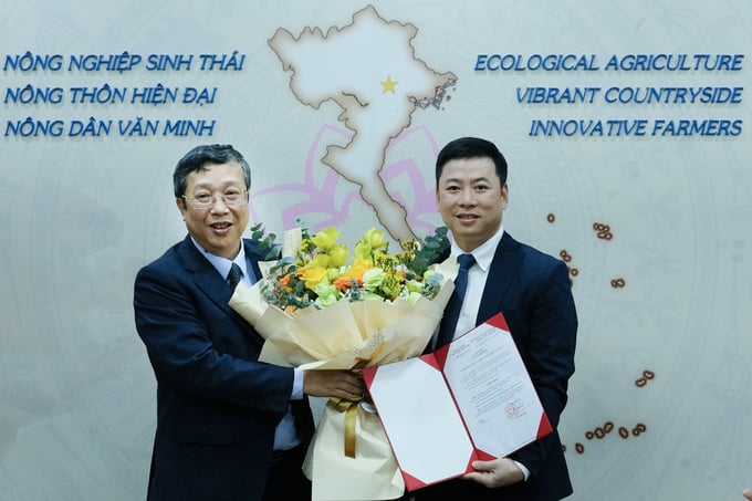 Thứ trưởng Hoàng Trung trao quyết định và hoa chúc mừng ông Trần Thế Công (bên phải) giữ chức Phó Vụ trưởng Vụ Hợp tác quốc tế sáng 2/2. Ảnh: Tùng Đinh.