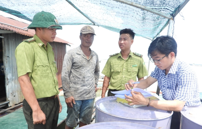 Cán bộ Chi cục Thủy sản tỉnh Đồng Nai cùng kiểm lâm địa phương vận động người dân ký cam kết không sử dụng các ngư cụ cấm. Ảnh: Trần Trung.