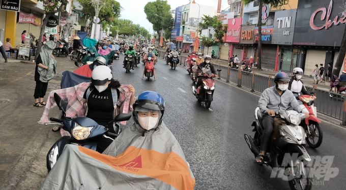 Cơn mưa bất chợt khiến nhiều người phải dừng vào lề đường để mặc áo mưa. Ảnh: Lê Bình.