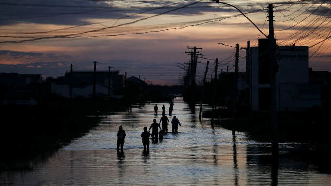 People walk along a flooded street of Eldorado do Sul, Rio Grande do Sul, Brazil on May 9. Photo: Anselmo Cunha AFP via Getty Images.