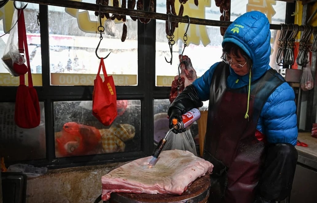 Nhân viên cửa hàng đang thui miếng thịt lợn tươi ở Sơn Đông, Trung Quốc. Ảnh: Xinhua. Nhân viên cửa hàng đang thui miếng thịt lợn tươi ở Sơn Đông, Trung Quốc. Ảnh: Xinhua.