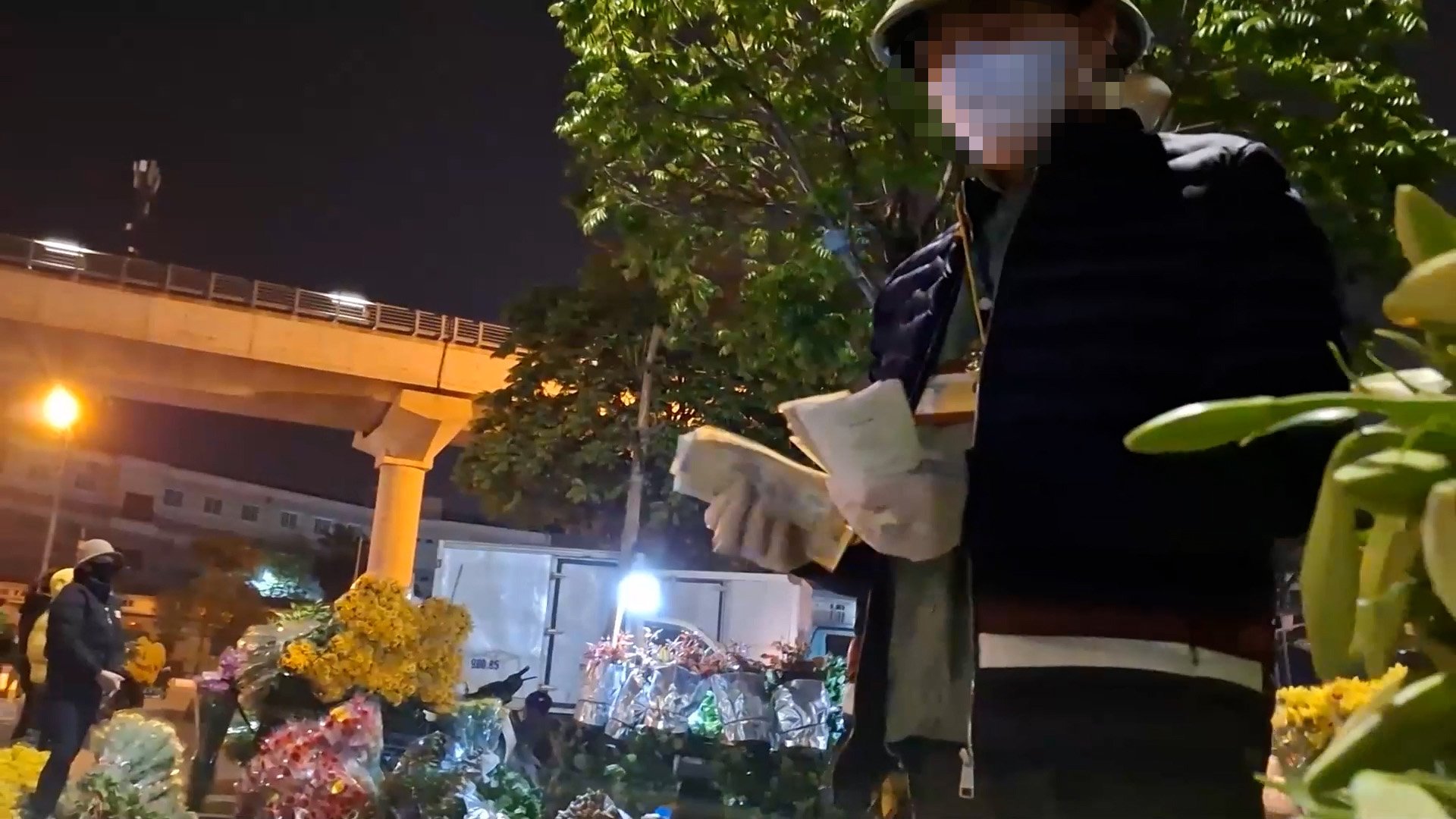 Người đàn ông tên Trung, kẻ được tiểu thương ví như 'người vận hành' của khu chợ ngầm, thu tiền, điều phối từng mét vỉa hè, từng chiếc xe hoa đỗ lại trong đêm. Ảnh: H.K.