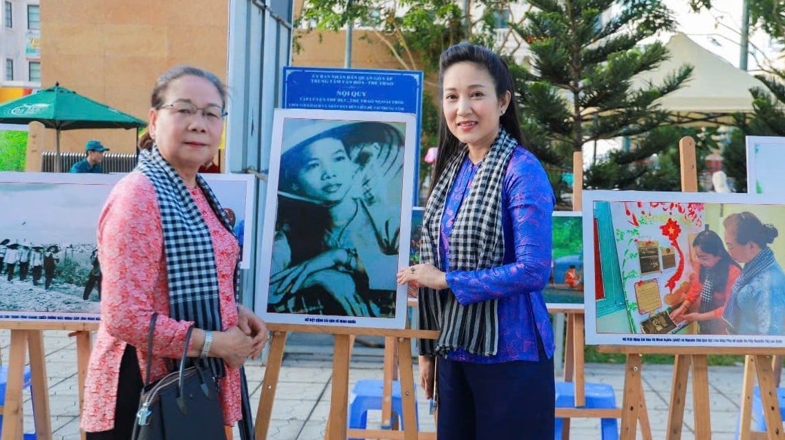 Bà Chính Nghĩa (bên trái) chụp kỉ niệm bên bức ảnh của mình thời còn tham gia Cách mạng. Ảnh: Đình Du. Bà Chính Nghĩa (bên trái) chụp kỉ niệm bên bức ảnh của mình thời còn tham gia Cách mạng. Ảnh: Đình Du.