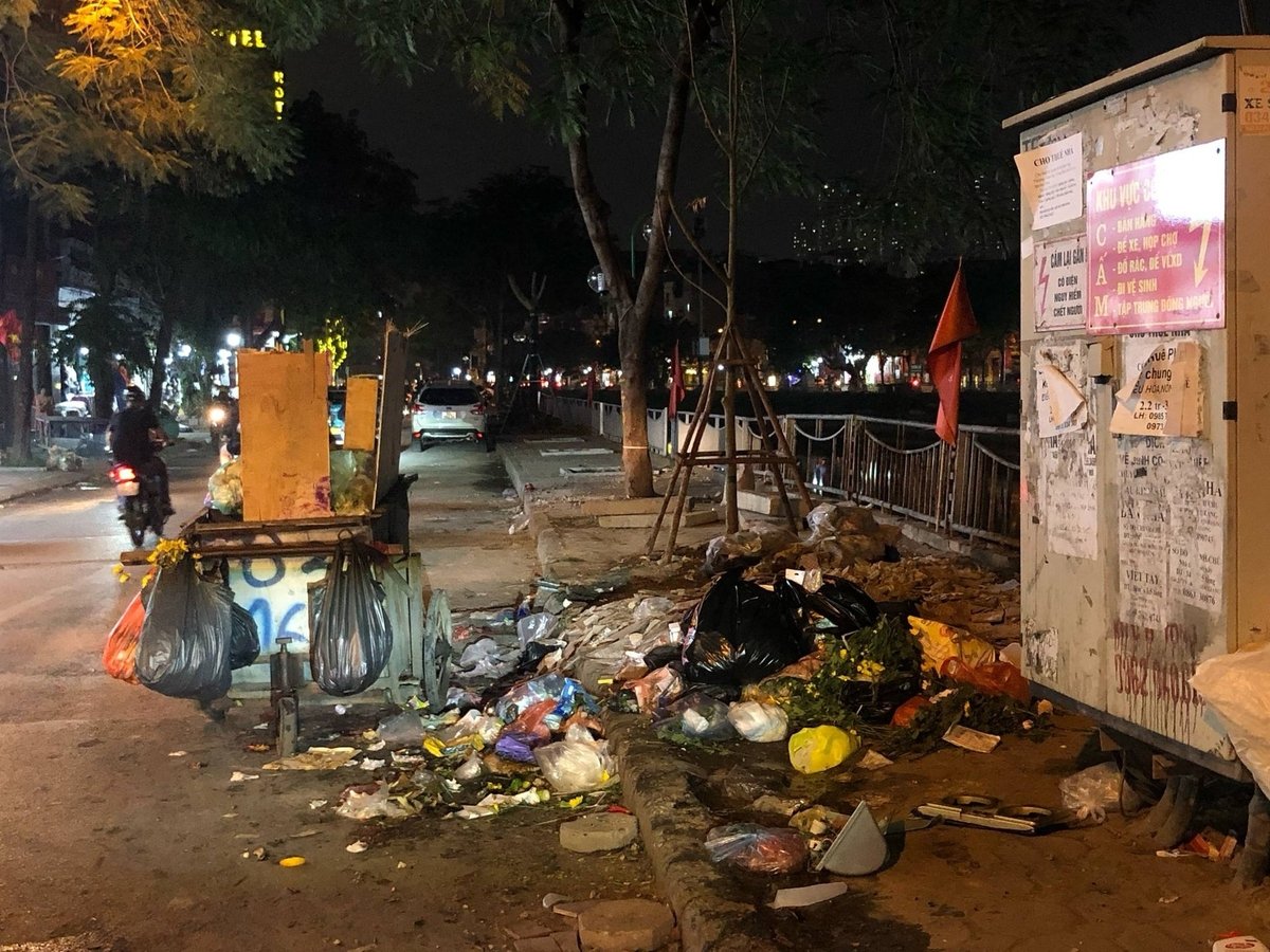Mặc dù có xe thu gom để bên cạnh, người dân vẫn vô tư vứt trên vỉa hè, vứt tràn ra lòng đường. Ảnh: Hoàng Hiền.