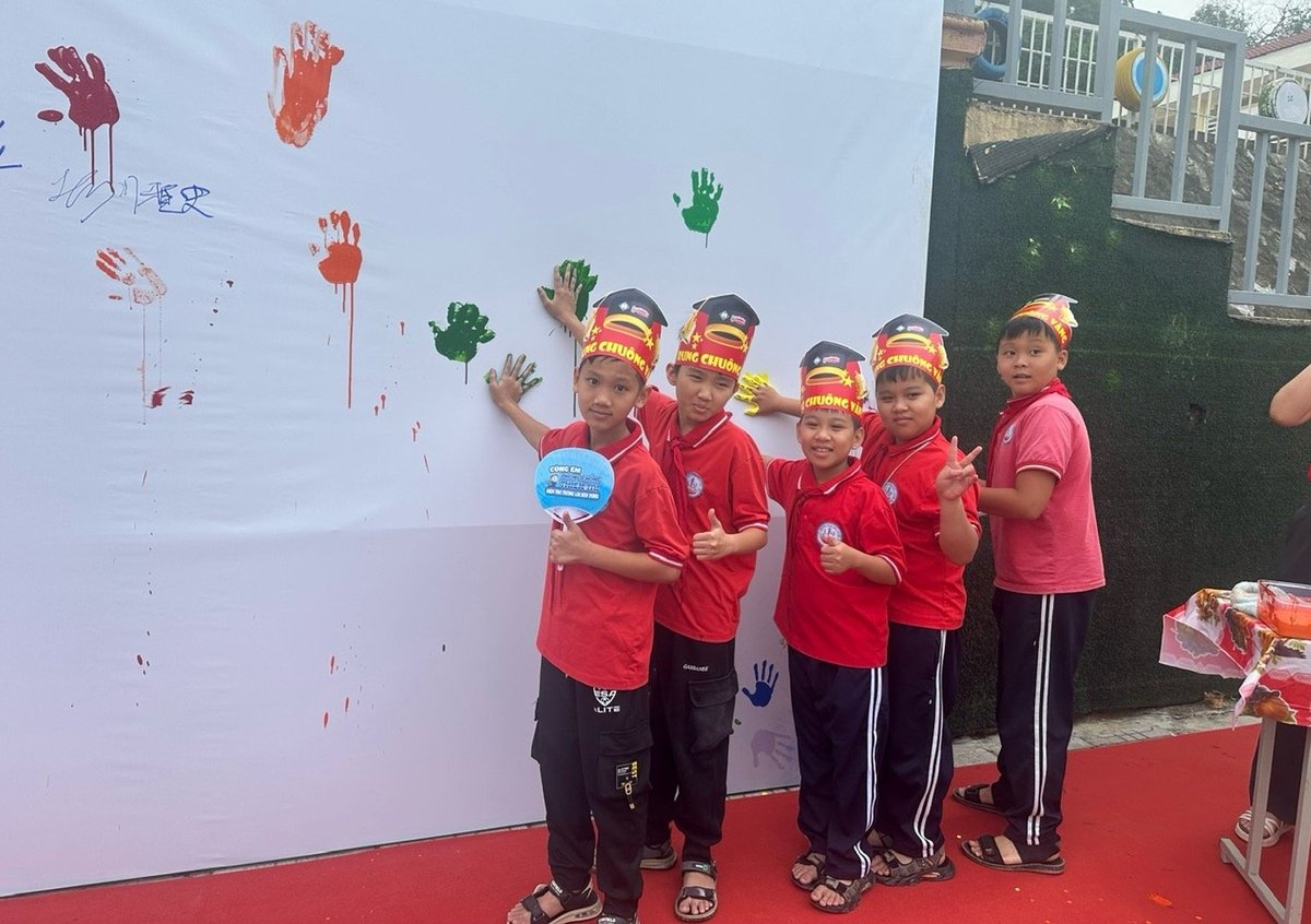 Các đại biểu và các em học sinh cùng in hình tay lên tấm bảng 'Công đồng bền vững, thích ứng thiên tai'. Ảnh: Bích Hợp. Các đại biểu và các em học sinh cùng in hình tay lên tấm bảng 'Công đồng bền vững, thích ứng thiên tai'. Ảnh: Bích Hợp.