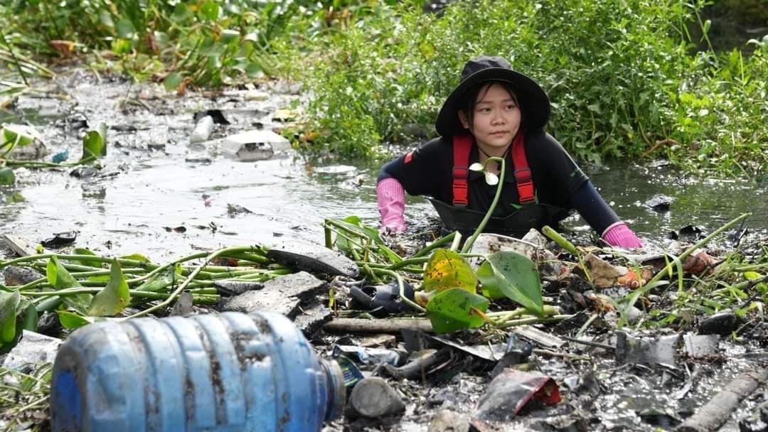 Một tình nguyện viên của Sài Gòn Xanh 'ngụp lặn' trong rác thải để làm sạch dòng kênh ô nhiễm. Ảnh: Thục Vy.