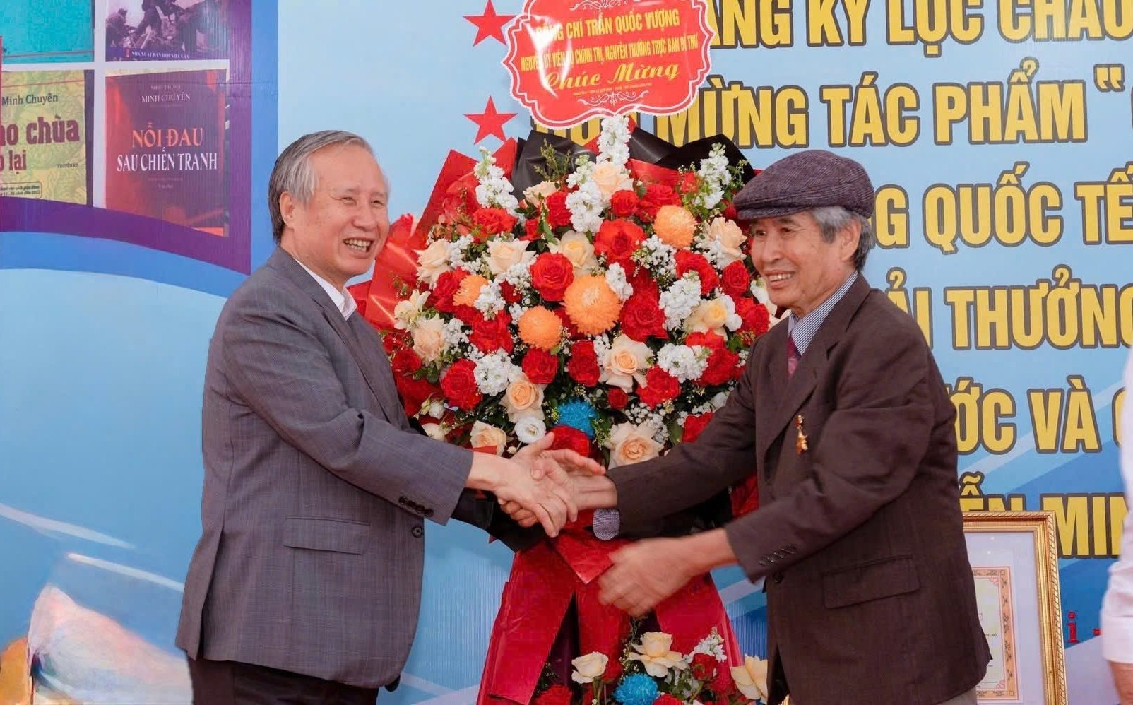 Ông Trần Quốc Vượng, nguyên Ủy viên Bộ Chính trị, Thường trực Ban Bí thư tặng hoa chúc mừng nhà văn, Anh hùng Lao động Minh Chuyên (phải). Ảnh: M.Hải.