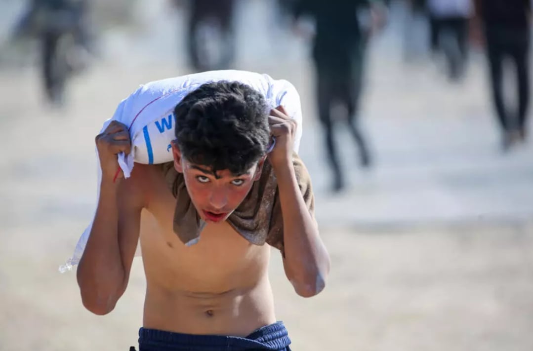 Một thiếu niên Palestine vác bao thực phẩm viện trợ trên vai sau khi xông vào kho hàng của WFP. Ảnh: Eyad BABA. Một thiếu niên Palestine vác bao thực phẩm viện trợ trên vai sau khi xông vào kho hàng của WFP. Ảnh: Eyad BABA.