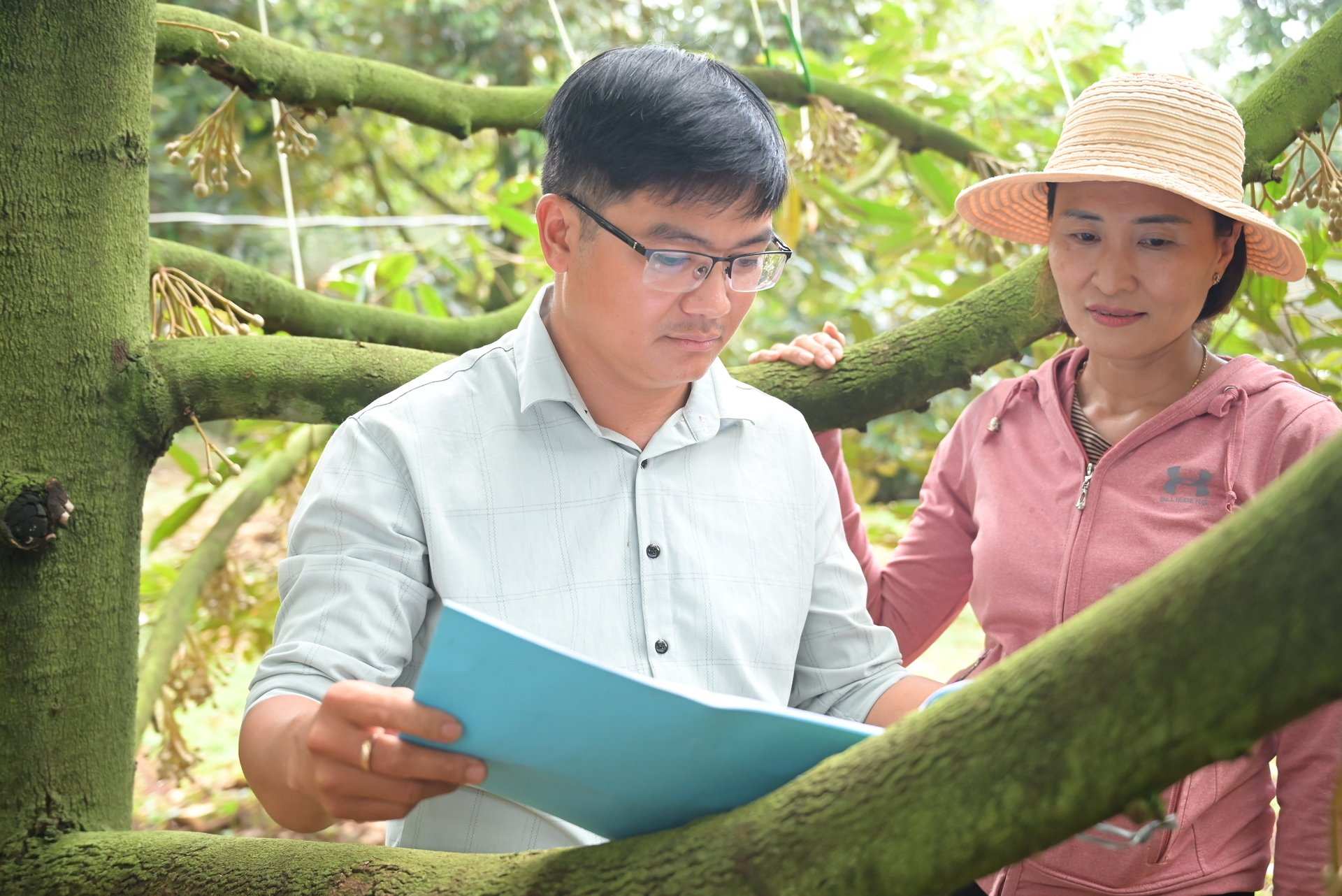 Cán bộ kỷ thuật của Công ty TNHH Thương mại nông sản Thiện Tâm hướng dẫn bà con nông dân cách chăm sóc vườn sầu riêng đạt hiệu quả. Ảnh: Phương Chi.