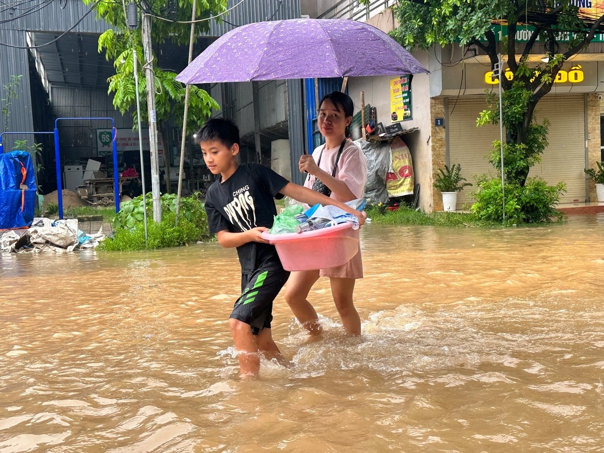Người dân mang theo đồ dùng ra khỏi khu vực ngập.