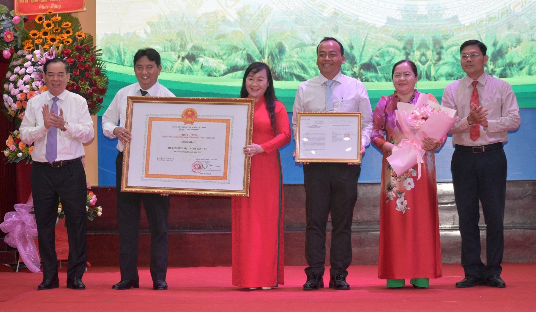 Ông Trần Ngọc Tam, Chủ tịch UBND tỉnh trao quyết định và bằng công nhận huyện nông thôn mới của Thủ tướng cho lãnh đạo huyện Bình Đại. Ảnh: Kiều Nhi.