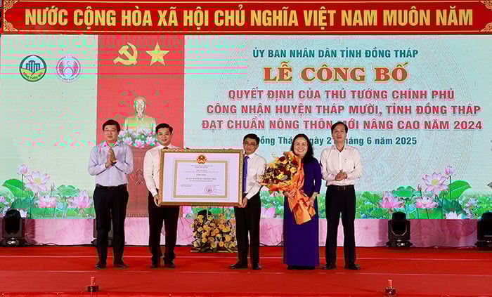 Bí thư Tỉnh ủy Đồng Tháp Lê Quốc Phong (bìa trái) trao bằng công nhận và hoa chúc mừng lãnh đạo huyện Tháp Mười. Ảnh: Lê Hoàng Vũ.