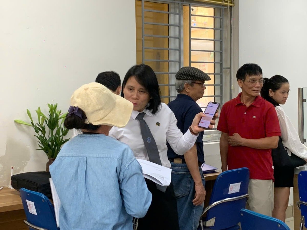 Cán bộ phục vụ hành chính công phường Tương Mai hướng dẫn người dân đến làm thủ tục hành chính trong sáng 1/7. Ảnh: Lan Chi.