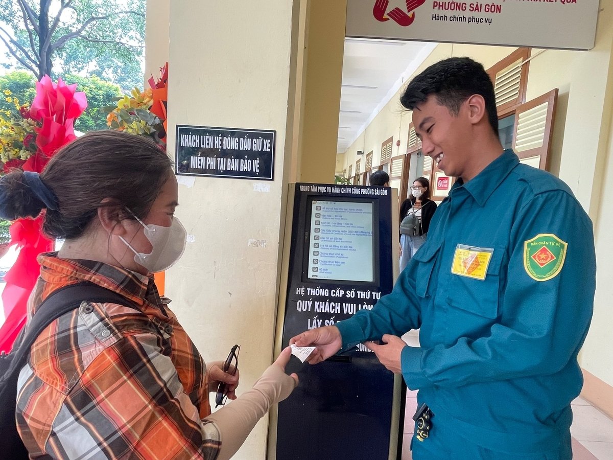 Anh Bảo Khang, dân quân phường Sài Gòn giúp người dân lấy số thứ tự. Ảnh: Đình Du.