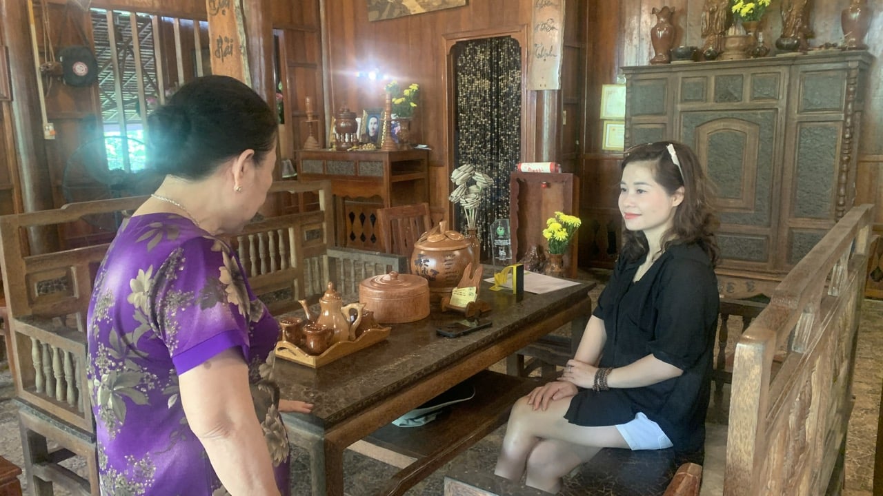 Visitors listen attentively as Mrs. Giac shares the unique story behind the coconut house. Photo: Ho Thao.