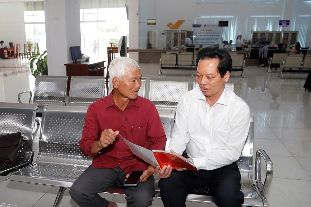 Ông Nguyễn Thành Diệu (bên phải), Phó Chủ tịch UBND tỉnh Đồng Tháp hỏi thăm ông Nguyễn Văn Ba khi đến thực hiện thủ tục hành chính tại Trung tâm Phục vụ hành chính công tỉnh Đồng Tháp. Ảnh: Minh Đảm.