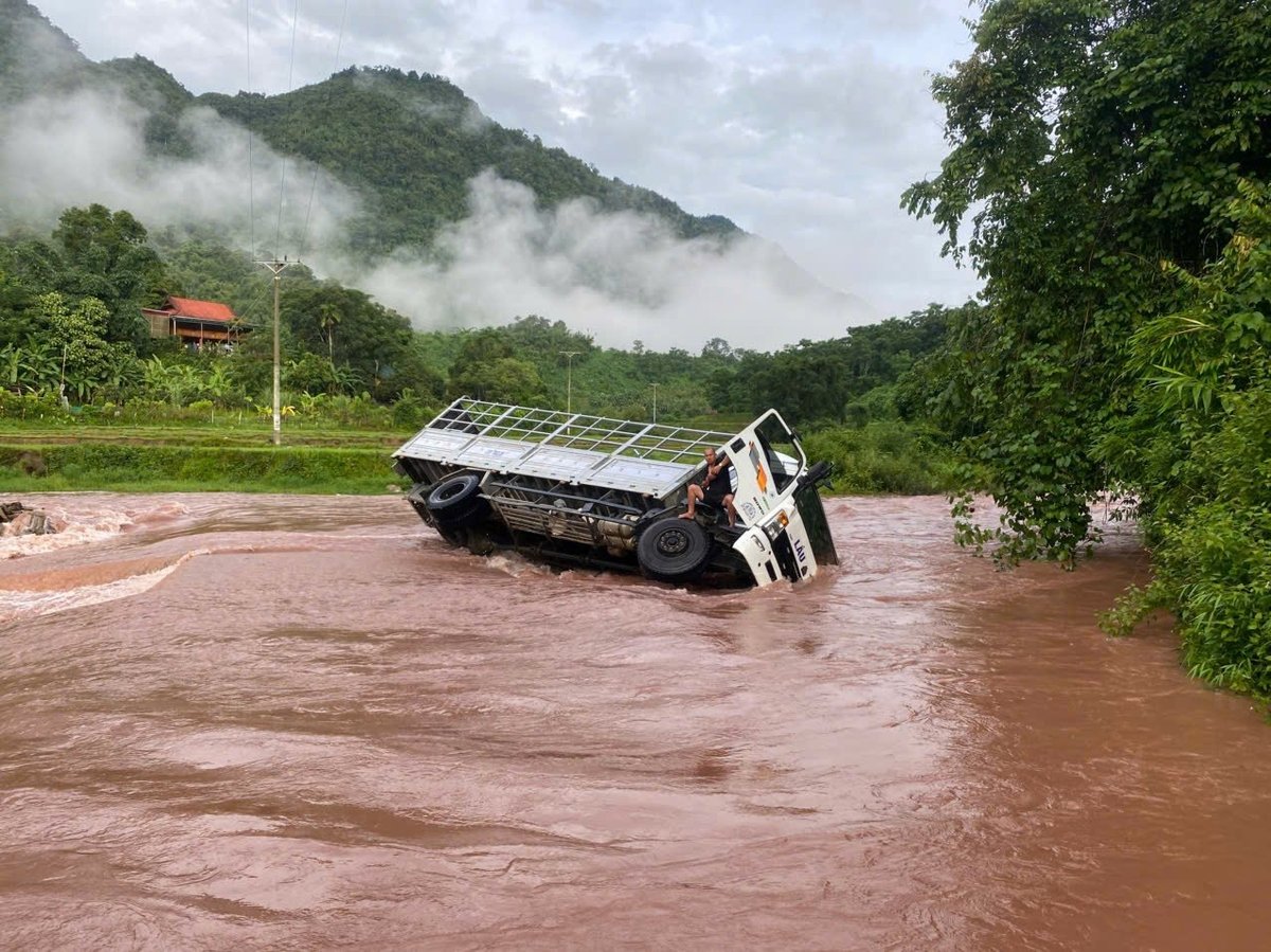 Chiếc xe tải bị lật nghiêng mắc kẹt giữa dòng nước lũ ở xã biên giới Na Loi. Ảnh: Vi Tuấn.