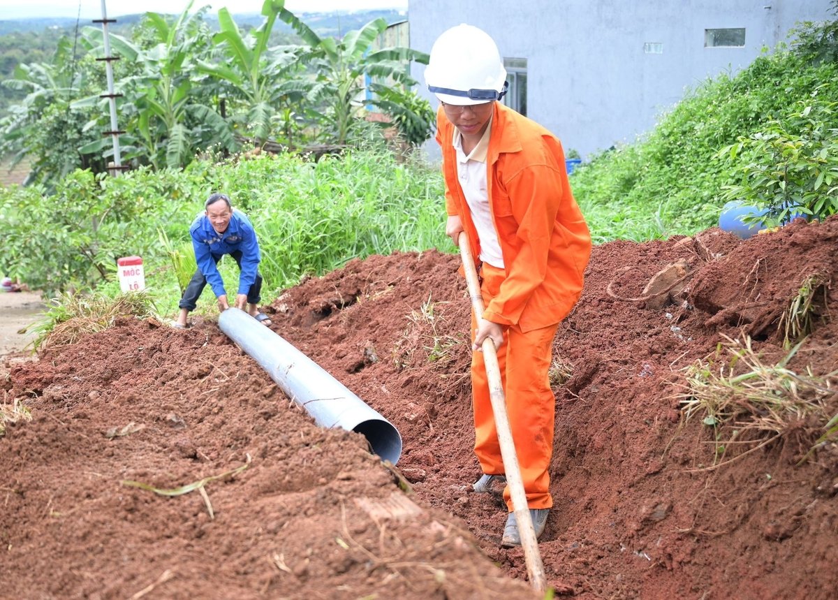 Cán bộ và công nhân Công ty Cổ phần BOT Đức Long Đắk Nông triển khai đào rảnh để đặt ống dẫn nước thoát xuống khu vực hạ du vào sáng 18/7. Ảnh: Phạm Hoài.