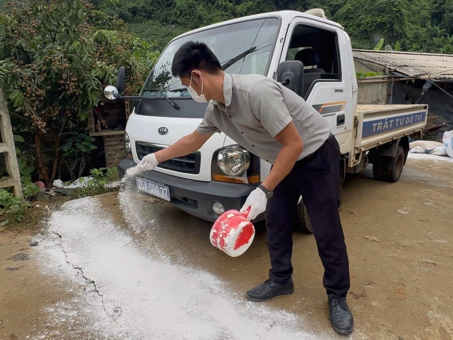 Cán bộ trung tâm kỹ thuật nông nghiệp XII rắc vôi bột quanh lối vào của gia đình ông Tổng. Ảnh: Đức Bình.