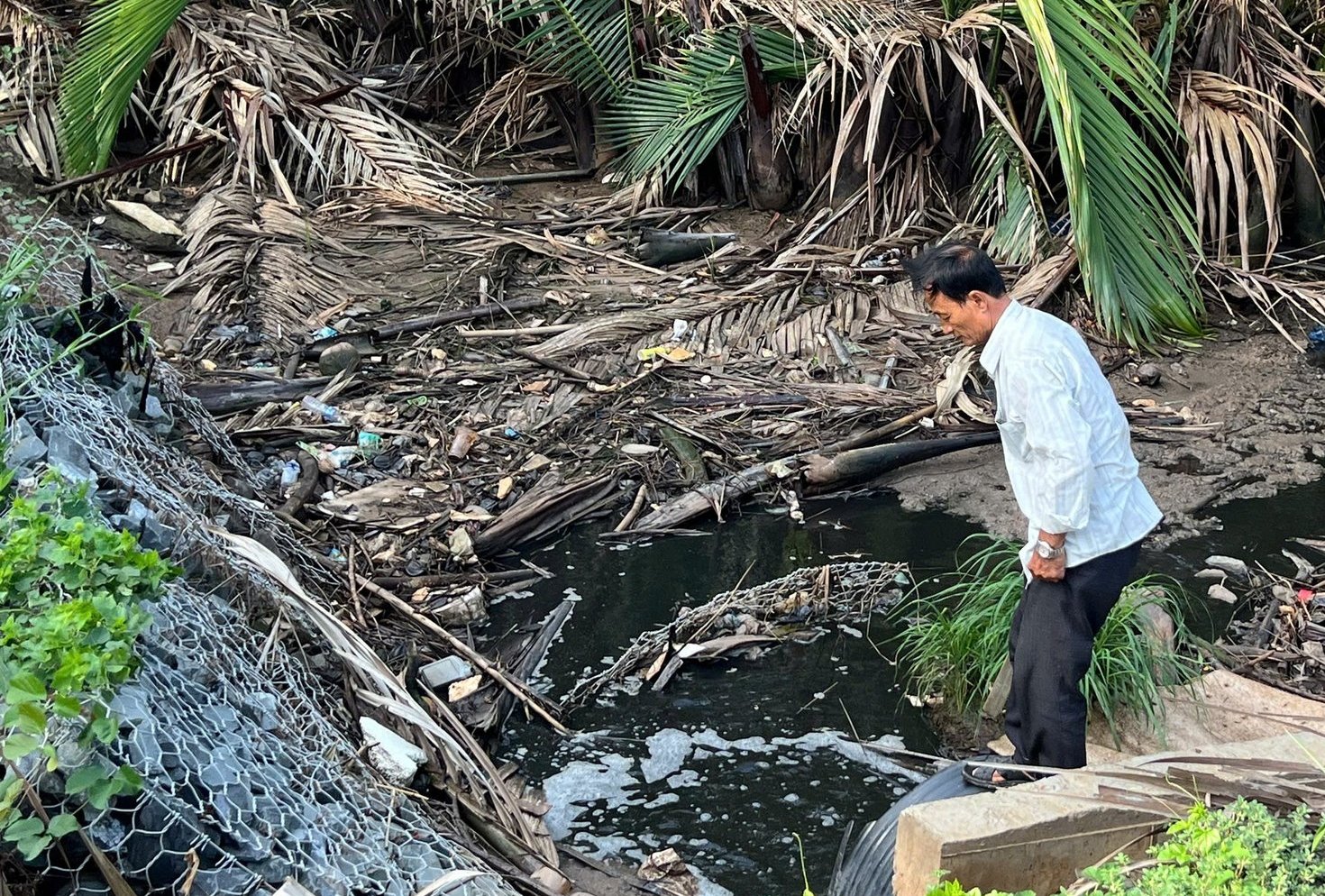 Ông Huỳnh Văn Châu chỉ ra nơi nước rỉ rác xả ra môi trường. Ảnh: Minh Đảm. Ông Huỳnh Văn Châu chỉ ra nơi nước rỉ rác xả ra môi trường. Ảnh: Minh Đảm.
