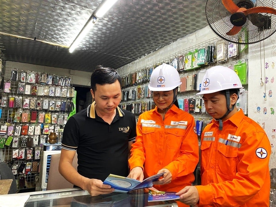 Công nhân điện lực tuyên truyền và phát cẩm nang an toàn điện đến khách hàng. Ảnh: PC Phú Thọ.
