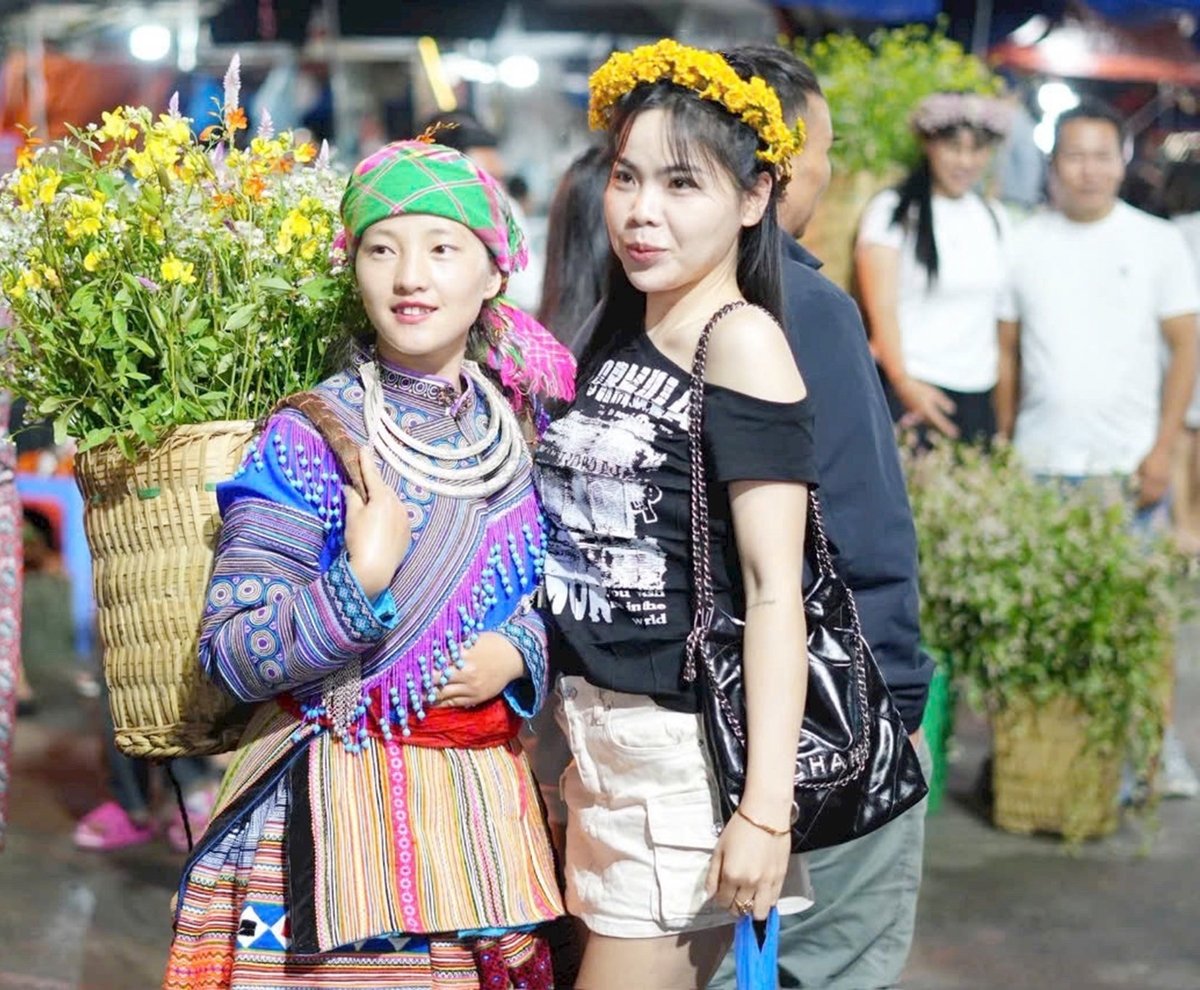 Du khách thích thú giao lưu và chụp ảnh cùng các thiếu nữ bản địa tại chợ văn hóa xã Bắc Hà. Ảnh: Thiên Hải.
